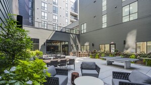 Un patio al aire libre con mobiliario, una mesa de ping pong y una parrilla.