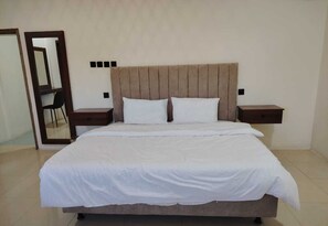 A bedroom with a bed, nightstands, a mirror, and a chair. - Alwaha towers hotels apartments  (Nejran)