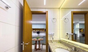 Un bagno moderno con lavandino, specchio e asciugacapelli.