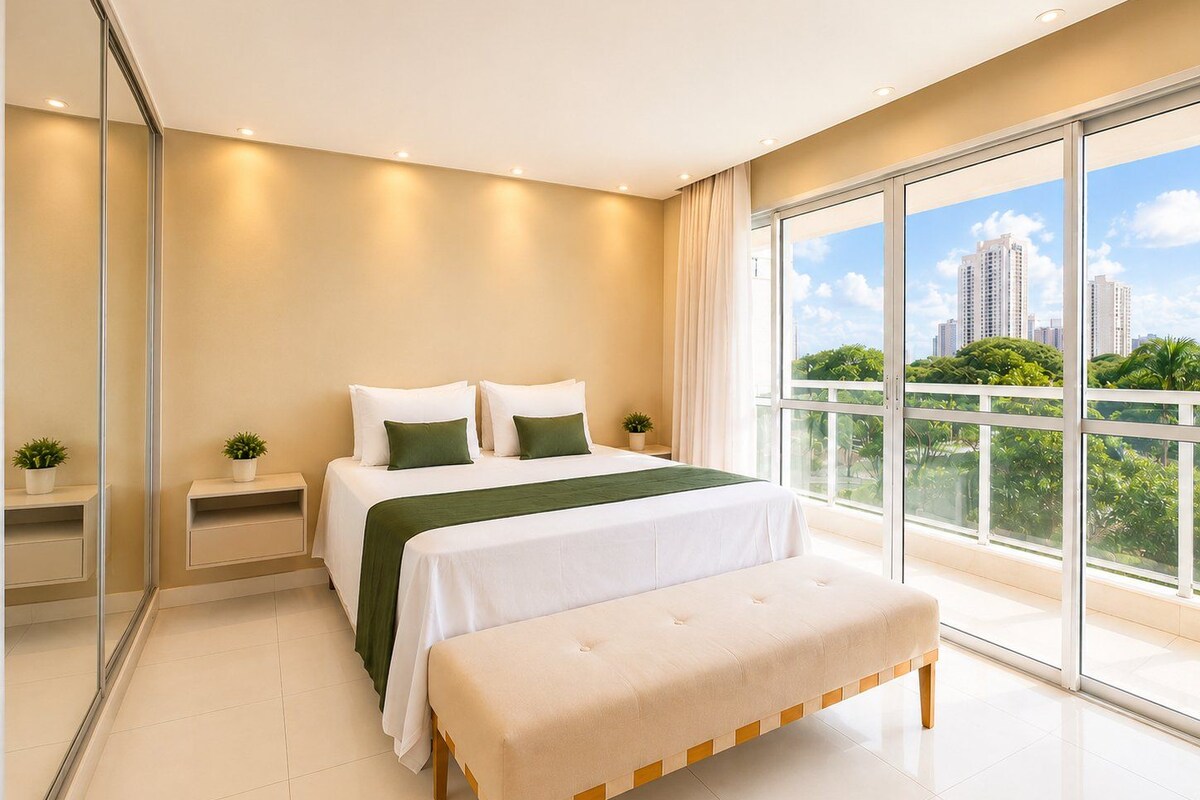 A modern bedroom with a large bed, a bench, a nightstand, and a view of a cityscape through large windows.