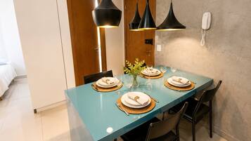 A dining area with a teal table, black chairs, and pendant lights.