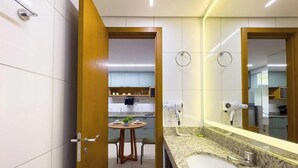 A modern bathroom with a large mirror, a sink, and a hairdryer mounted on the wall.