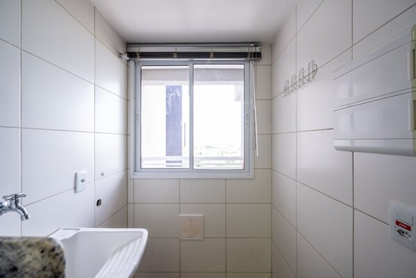 A bathroom with white tiles, a window, a sink, and a ventilation system. - The Expression (Goiânia)