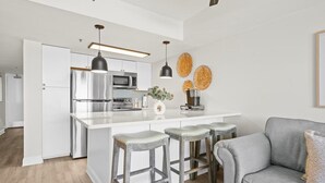 Een moderne keuken met witte kasten, roestvrijstalen apparatuur en een centraal keukenblok met barstoelen.