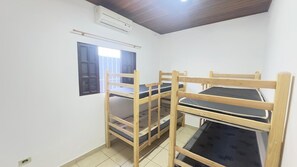 Ein Zimmer mit Etagenbetten, einem Fenster mit Rollläden und einer Klimaanlage an der Wand.