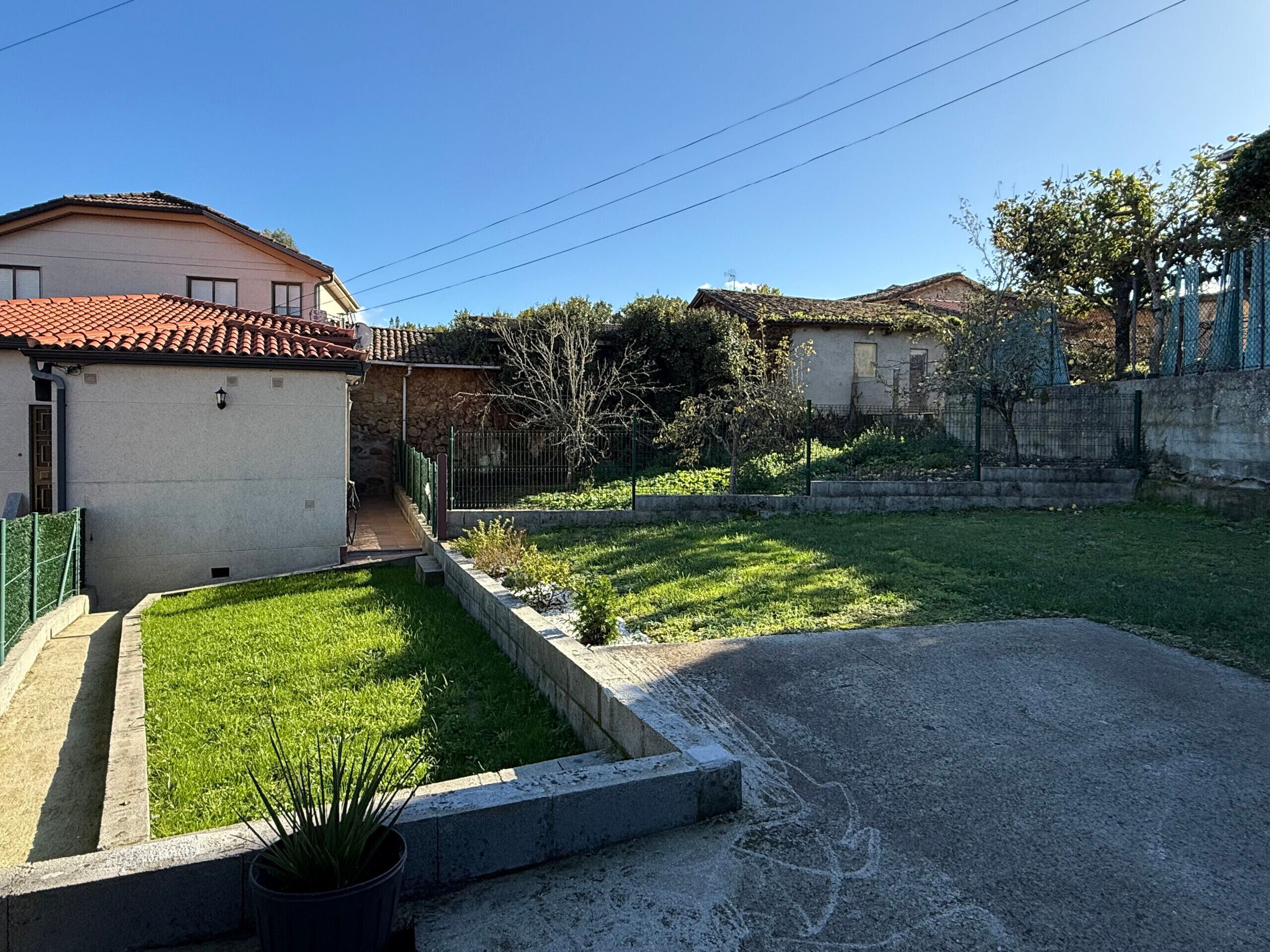 Un quartier résidentiel avec une allée pavée, une pelouse bien entretenue et un mur en pierre.