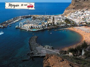 Eine Küstenstadt mit einem Yachthafen, Strand und felsigen Klippen.