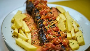 Un plato con pescado a la parrilla, patatas en cubos y salsa de tomate.