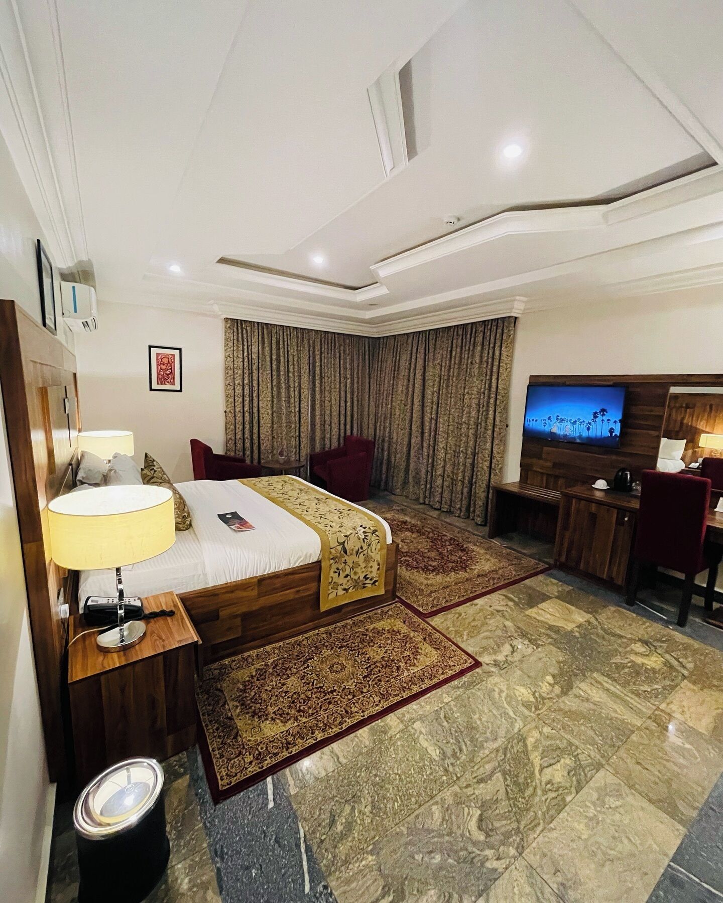 A hotel room with a bed, a desk, a TV, and a bathroom.