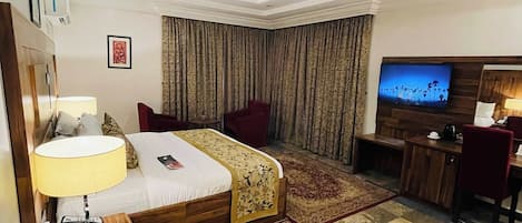 A hotel room with a bed, a desk, a TV, and a bathroom.