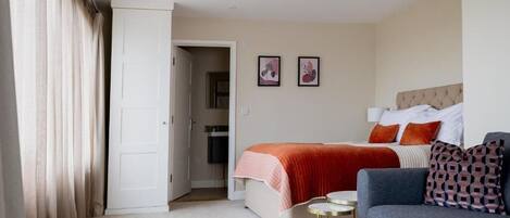 A hotel room with a bed, a sofa, a small round table, and two framed pictures on the wall.