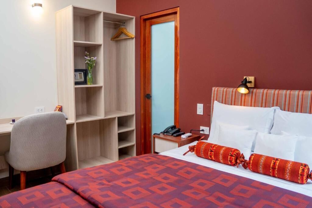A hotel room with a bed, a desk, a wardrobe, and a bedside table.