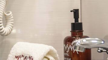 A bathroom with a white towel, a bottle of liquid soap, and a telephone.