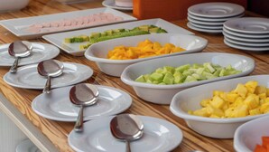 Un bufé con una variedad de alimentos y bebidas, incluyendo frutas, verduras y jugos.