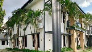 A modern two-story house with a flat roof, large windows, and a paved driveway with grass inlays. - Muftyz Shortlets (Abuja)
