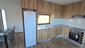A modern kitchen with wooden cabinets, a built-in oven, and a refrigerator. - 6 holiday homes in the tranquillity of nature near Barcelos (Roriz)