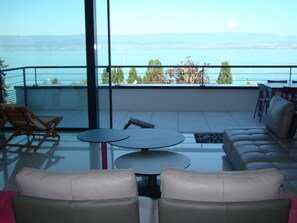Un balcon donnant sur une étendue d’eau, avec une table et des sièges.
