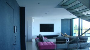 A modern living room with a sofa, a flat-screen TV, and a staircase. - Air-conditioned house 8 pers- 10km Evian -40km portes soleil- with parking lot (Thonon-les-Bains)