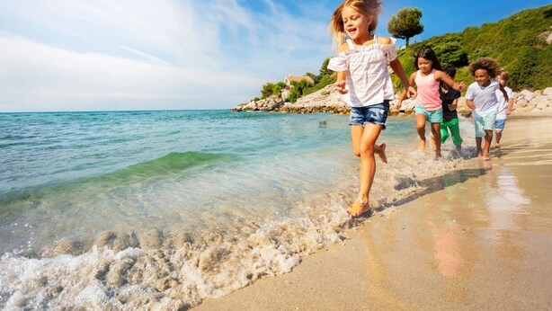 Una playa con agua cristalina y costa rocosa.