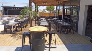 Un patio al aire libre con mesas y sillas, una pérgola de madera y un cubo de basura.