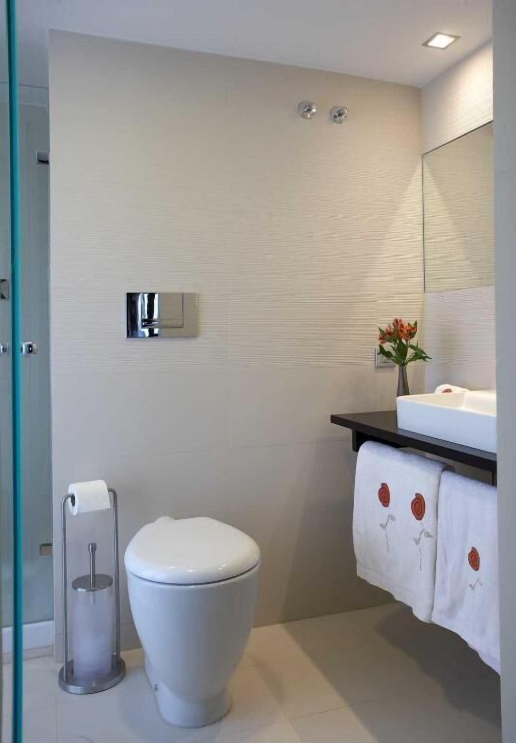 A modern bathroom with a toilet, a sink, and a mirror.