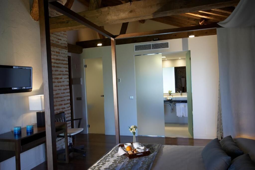 A modern living room with a flat-screen TV, a dining area, and a kitchen visible through an open doorway.