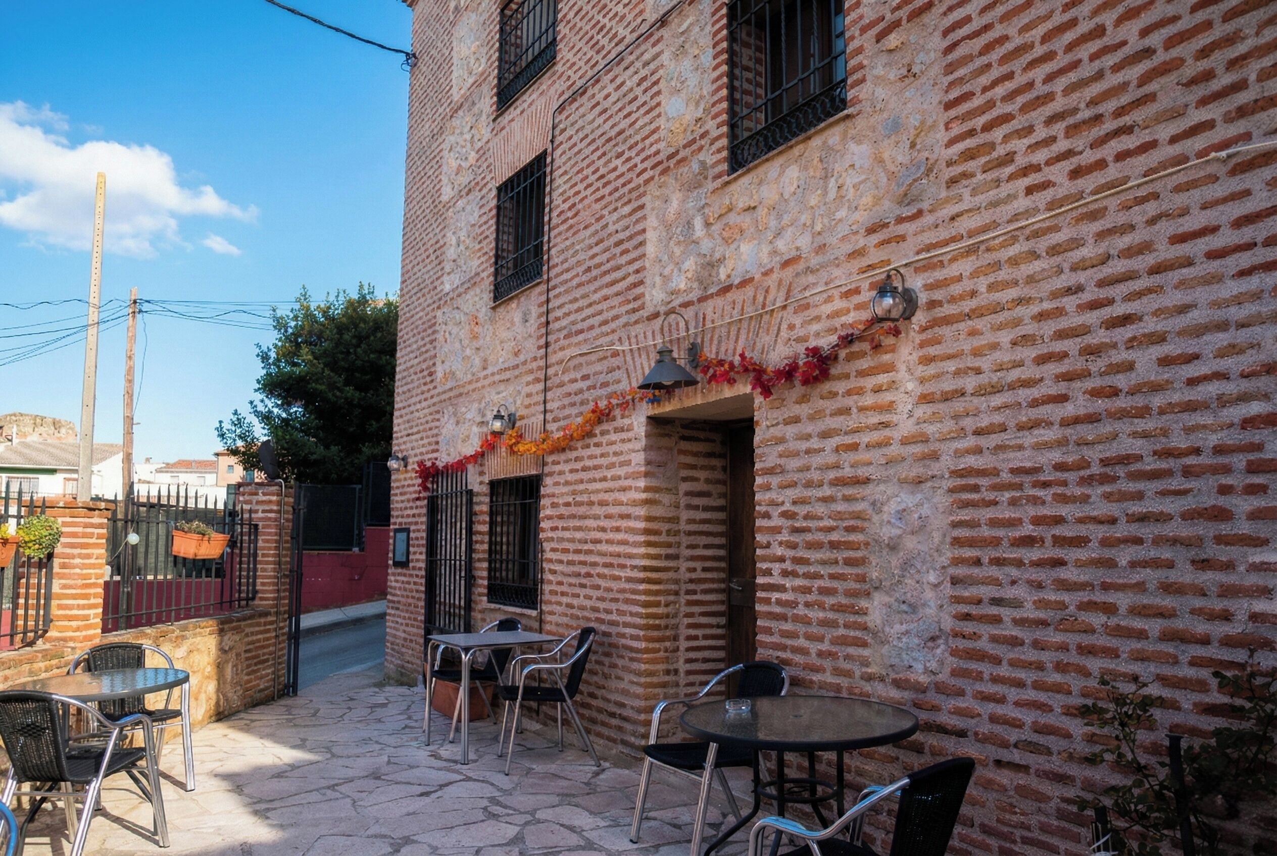 A courtyard with outdoor seating, brick walls, and a clear sky.