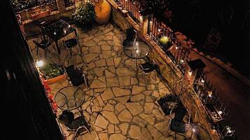 An outdoor patio area with stone flooring, multiple tables and chairs, and a railing along the perimeter.