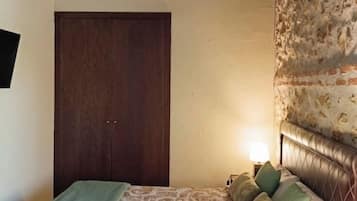 Ein Schlafzimmer mit einem Bett, einem Nachttisch, einer Lampe und einer Holzbalkendecke.