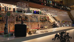 Un espace bar avec une variété de bouteilles d’alcool et de verres disposés sur des étagères.