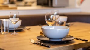 Una mesa de comedor con un tazón, platos y copas de vino.