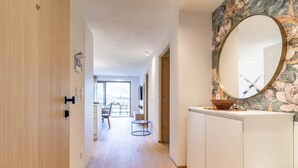 Un pasillo con una puerta de madera, un armario blanco con espejo y vistas a un balcón.