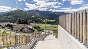 Una escalera conduce a una valla de madera con vistas a un valle con casas y montañas.