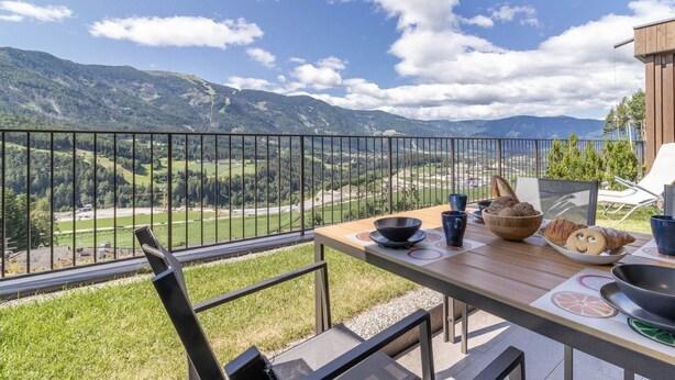 Un balcón con una mesa dispuesta para el desayuno, con vistas a un paisaje montañoso.