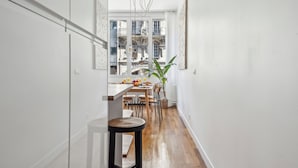Un pasillo estrecho con un comedor que incluye una mesa de madera, sillas y una planta en maceta.