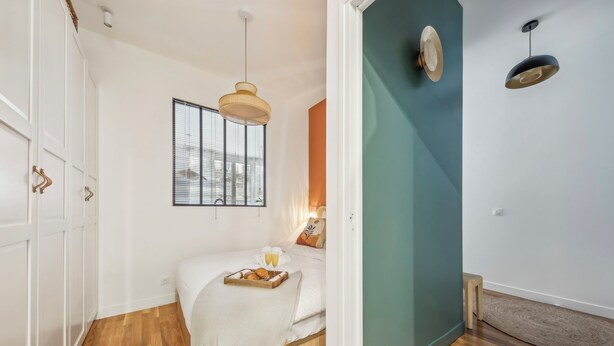 Un dormitorio con cama, mesita de noche y ventana con persianas.