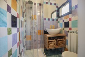 Een badkamer met een douche, wastafel, spiegel en toilet.