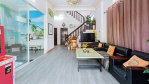 Un salón amplio con escalera, televisor de pantalla plana y una mesa de centro.
