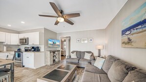 Ein modernes Wohnzimmer mit einem grauen Sofa, einem Couchtisch und einem Deckenventilator.