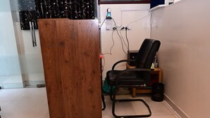 A small room with a wooden desk, a black office chair, a green bag, and a black trash bin. - Hotel Vinayak Near Akshaya Patra Jagatpura (Jaipur)