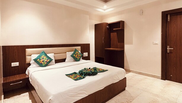 A bedroom with a large bed, wooden headboard, a ceiling fan, and a wardrobe. - Hotel Vinayak Near Akshaya Patra Jagatpura (Jaipur)