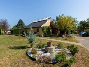 Ein Wohnhaus mit Satteldach, ein Garten mit kreisförmigem Steinbecken und eine Auffahrt zu einem geparkten Auto.