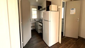 Cozinha compacta com geladeira embutida, uma janela e uma porta com um letreiro.