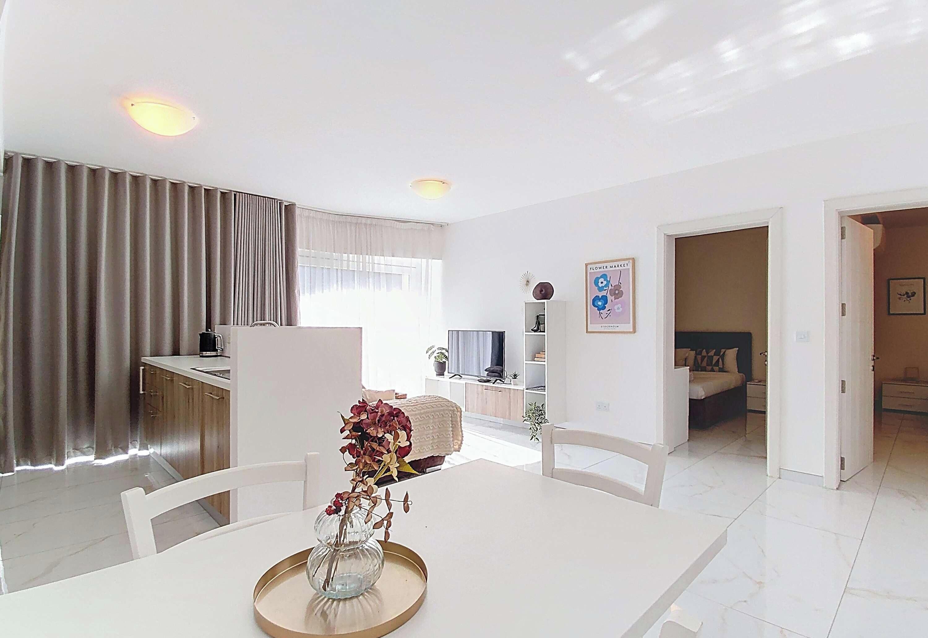 A modern living room with a dining table, a TV, and a sofa.