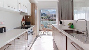 Een moderne keuken met witte kasten, een zwart fornuis en een eethoek met een stoel en tafel.