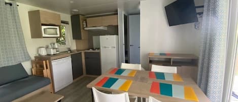 A compact room with a kitchenette, a dining area with a colorful table, and a sofa.