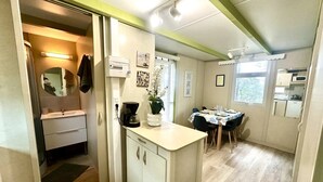 Une cuisine compacte équipée d’un évier, d’une machine à café et d’un petit coin repas avec une table et des chaises.