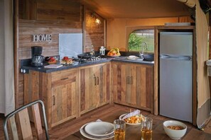 Eine kleine Küche mit Holzschränken, einer Kaffeemaschine, einem Herd und einem Kühlschrank.