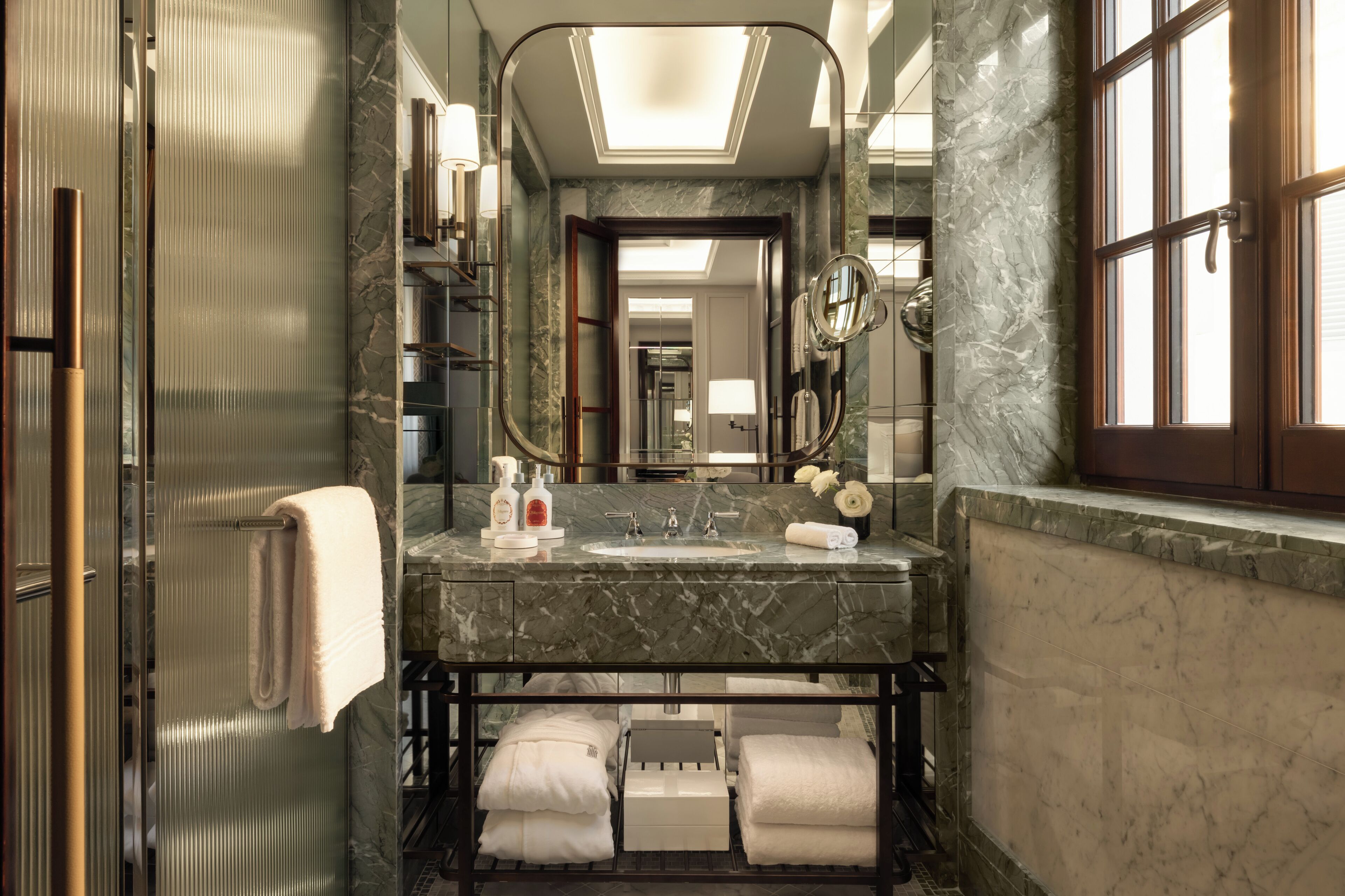 Une salle de bain moderne avec un lavabo en marbre, un grand miroir et une douche à parois de verre.