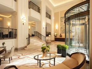 Eine großzügige Lobby mit einer imposanten Treppe, einem Empfangsbereich und einem großen Fenster mit Blick.